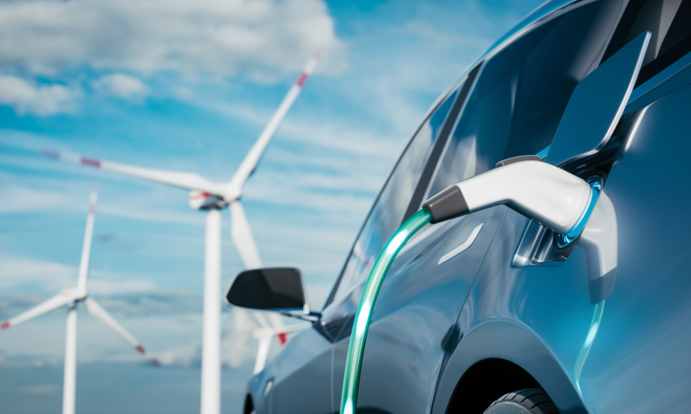 Electric vehicle (EV) being charged in front of wind turbines, symbolizing sustainable energy and eco-friendly transportation